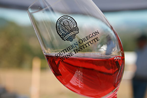 A close-up of a wine glass filled with pink wine, featuring the logo of the Southern Oregon Wine Institute.